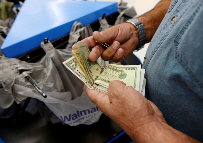 A customer counts his cash at the checkout lane of a Walmart store in the Porter Ranch section of Los Angeles.