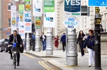 A man cycles past posters in central Dublin ahead of a fiscal treaty referendum in Ireland.