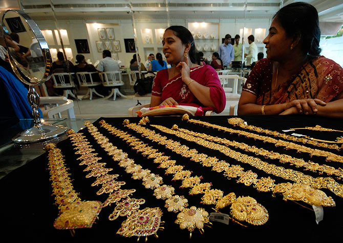 A customer looks in a mirror after wearing a gold earring inside a jewellery shop in Hyderabad.
