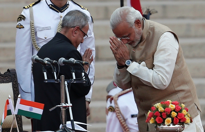 Prime Minister Narendra Modi (R) greets President Pranab Mukherjee after taking his oath at the presidential palace in New Delhi May 26, 2014.