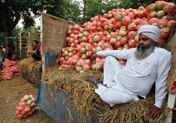A farmer sits on a trolley loaded with melons as he waits for customers at a fruit and vegetable market in Chandigarh.