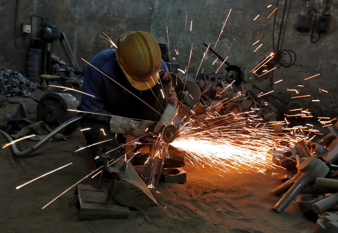A worker grinds a metal shaft metal used in water pumps at a manufacturing unit on the outskirts of Ahmedabad.