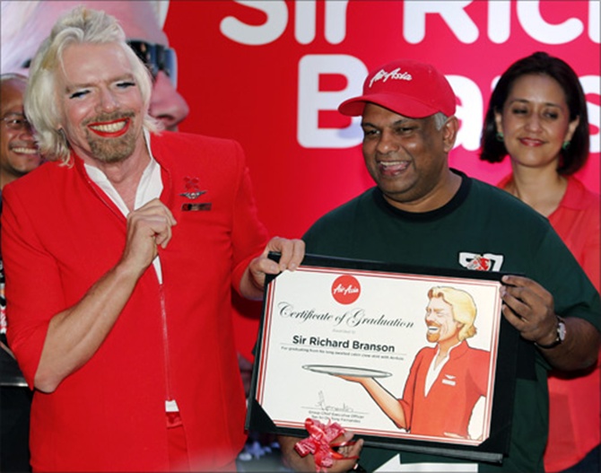 AirAsia's Chief Executive Tony Fernandes (R) presents a certificate to British entrepreneur Richard Branson.
