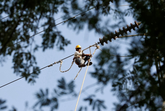 An employee for the Paschim Gujarat Vij Company Ltd. sets up power lines at Gandhinagar.