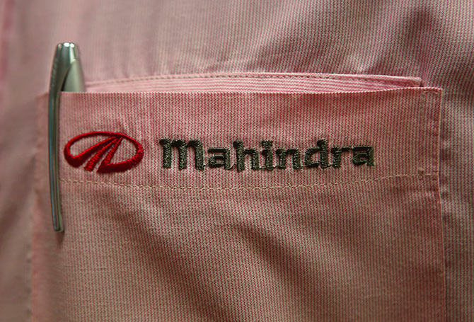 The logo of Mahindra & Mahindra Ltd is pictured on the pocket of a salesman's shirt as he poses inside the company's showroom.