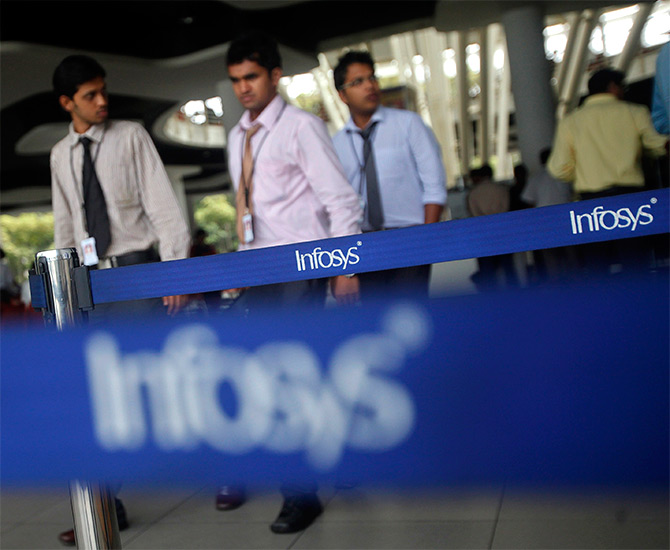 Employees of Indian software company Infosys walk past Infosys logos at their campus in the Electronic City.