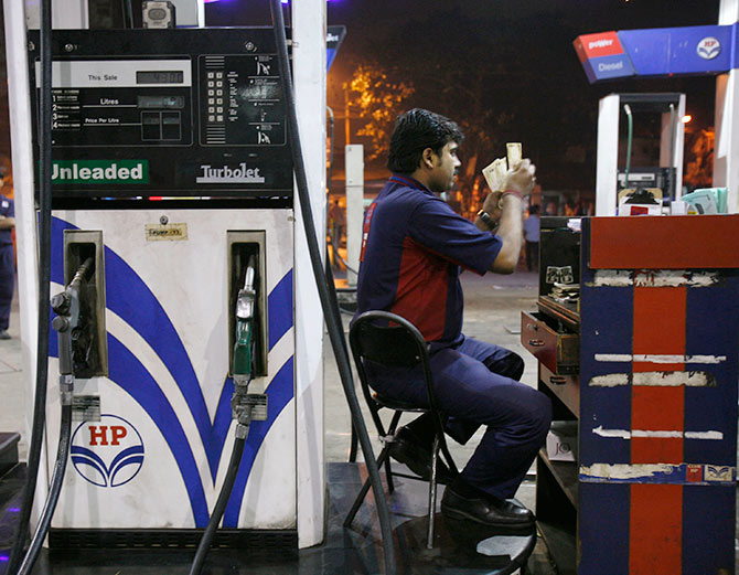 A worker (R) counts currency at a petrol pump in Kolkata.
