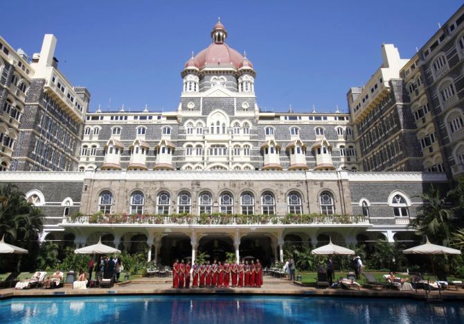 Staff of the Taj Mahal Palace hotel pose for a photo near the hotel's swimming pool.