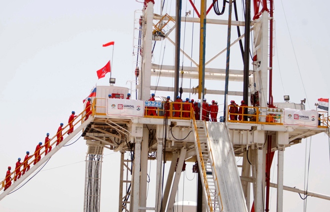 Workers from Russia's LUKOIL watch during the start of drilling for the first out of 23 oil wells to be drilled at West Qurna oilfield in Basra, 420 km (260 miles) southeast of Baghdad.