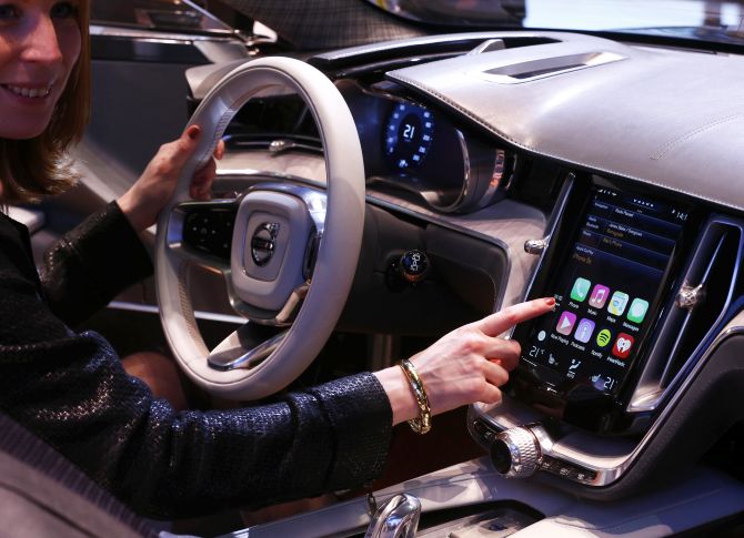 A woman touches the display inside a Volvo car.