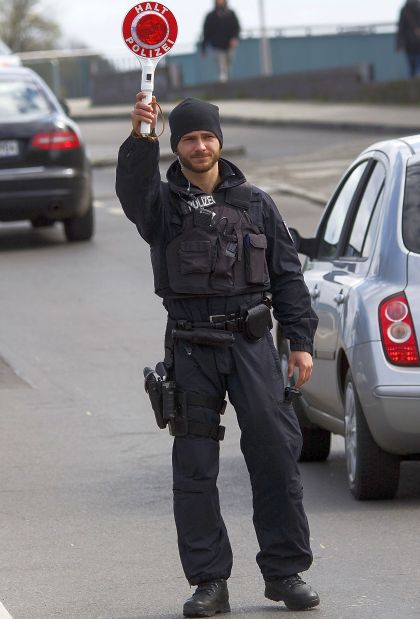 A German policman holds a police signal stick to stop cars.