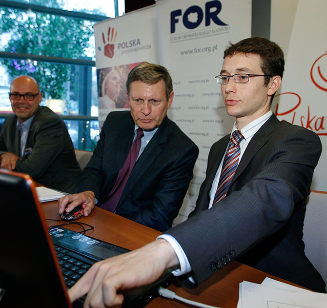 Wiktor Wojciechowski (R) from the Civic Development Forum points on a computer as Poland's former Central Bank Governor Leszek Balcerowicz launches a public debt counter on a public screen in Warsaw.