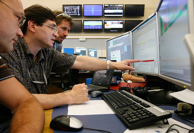 Scientists look at computer screens at the Large Hadron Collider (LHC) control center of the CERN in Geneva.