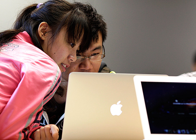 People look at an Apple computer during the inauguration of a new Apple store in Nanjing Road, downtown Shanghai.