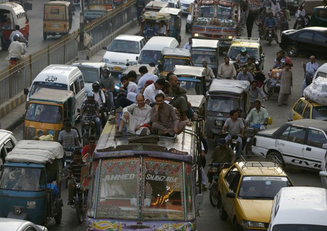 People sit atop a van in the traffic in Karachi.