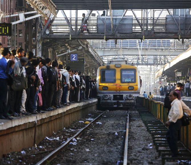 Commuters wait on a crowded railway platform as a train enters a suburban station in Mumbai.