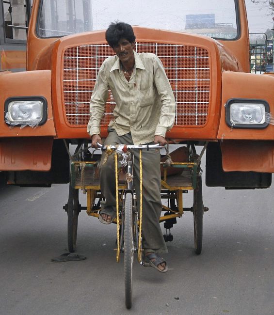 A man uses a cycle rickshaw to transport the front portion of a supply truck.