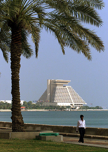 A man walks on the promanade across the bay from a luxurious hotel in Doha.