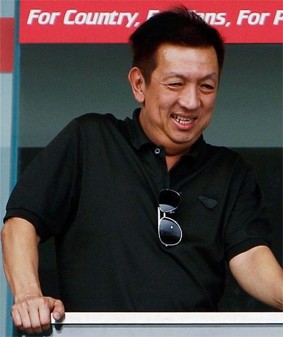 Singaporean billionaire Peter Lim (L) watches a soccer clinic for school children conducted at Jalan Besar Stadium in Singapore.