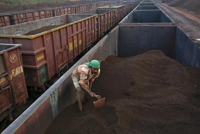 A worker levels the iron ore in a freight train at a railway station at Chitradurga in Karnataka.