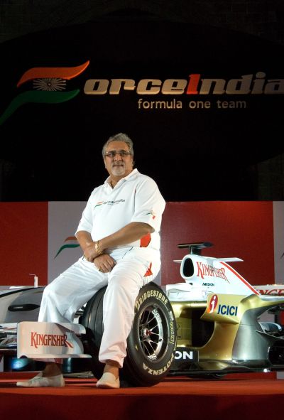 Chairman of Force India F1 team, Vijay Mallya, poses with the Force India Formula One Team car.