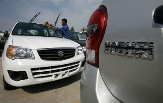 A worker cleans a parked car at the Maruti Suzuki's stockyard.