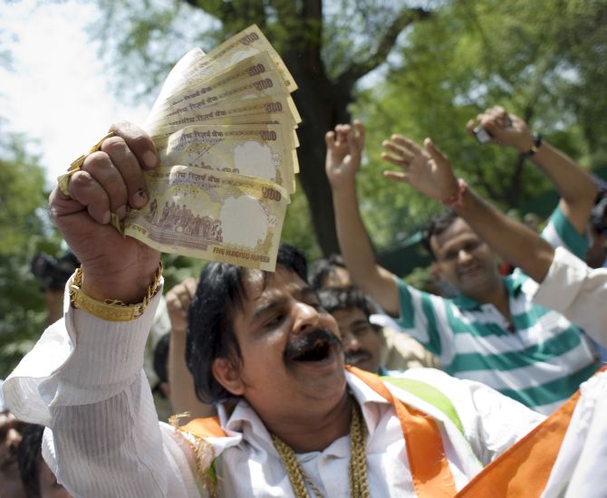 A man hands out money as supporters celebrate election results in front of the headquarters of the Congress Party.