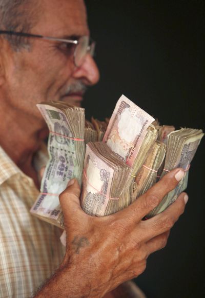 A man holds currency notes near a cash counter after withdrawing them inside a bank on the outskirts of Jammu.