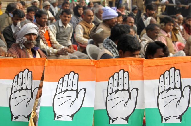 Supporters of India's ruling Congress party sit next flags of party's logo as they attend an election campaign rally addressed by Rahul Gandhi.