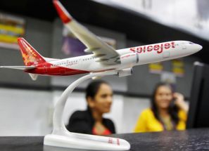  Employees at a travel agency office working besides a model of a SpiceJet aircraft.