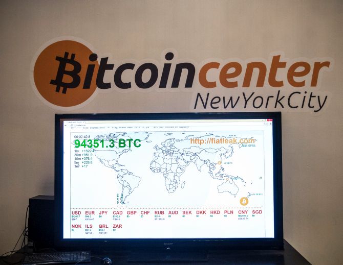 A television screen displays various bitcoin rates at Bitcoin Center NYC.