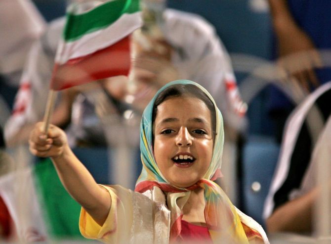 An girl waves an Iranian flag during a football game between Iran against Oman in the in Jeddah, Saudi Arabia.