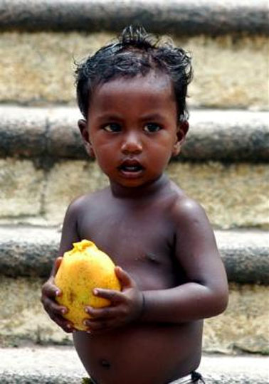 A homeless Indian child holds a mango in Chennai.