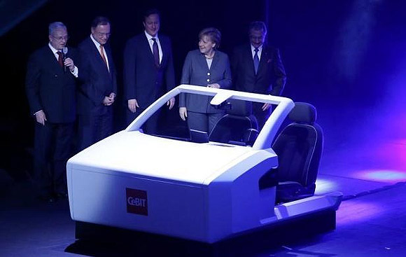 Volkswagen Chief Executive Martin Winterkorn, Prime Minister of Lower Saxony Stephan Weil, British Prime Minister David Cameron, German Chancellor Angela Merkel and President of the German Association for Information Technology, Telecommunications and New Media BITCOM Dieter Kempf look at a model of a car which drives itself.