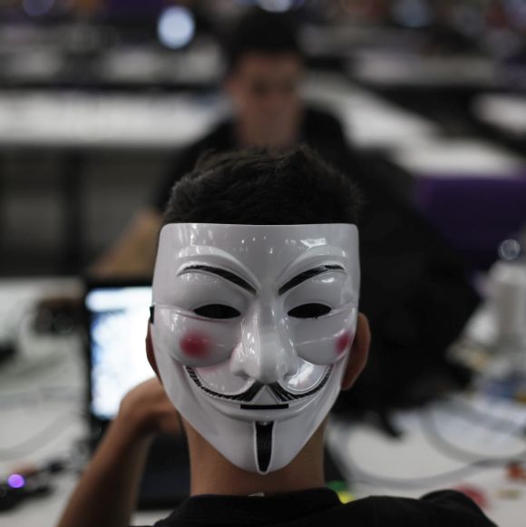 Image: A man wearing a Guy Fawkes mask surfs the web. Photographs: Nacho Doce/Reuter