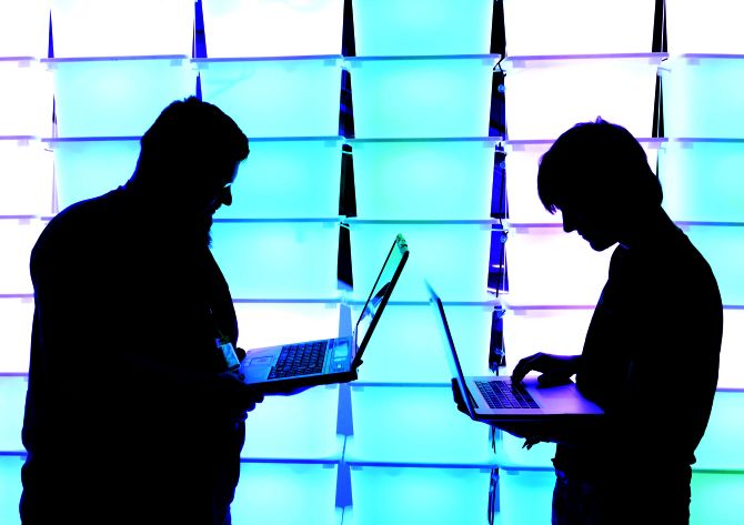 Participant hold their laptops in front of an illuminated wall.