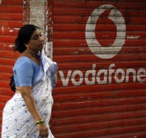 A woman walks past a large logo of Vodafone displayed on a shop in Mumbai
