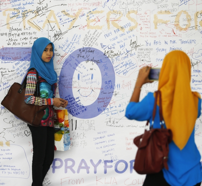A girl has her picture taken after leaving messages of support and hope for the passengers of the missing Malaysia Airlines MH370 at the Kuala Lumpur International Airport