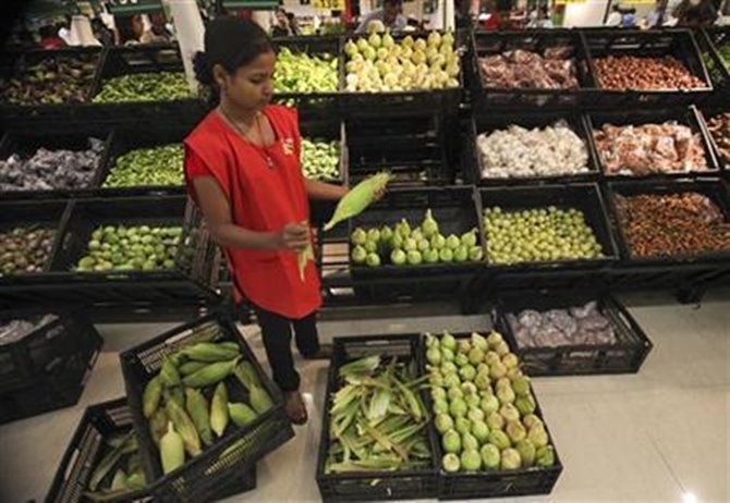 An employee arranges vegetables in the fresh foods section of a Reliance Fresh supermarket.