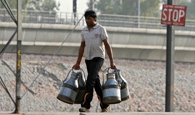 A milkman carries empty milk containers at a railway platform in New Delhi 