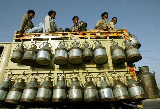 Milkmen sit on top of a truck with milk containers in New Delhi.
