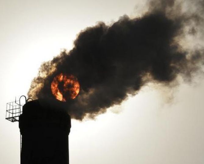 The sun is seen behind smoke billowing from a chimney of a heating plant in Taiyuan, Shanxi province.