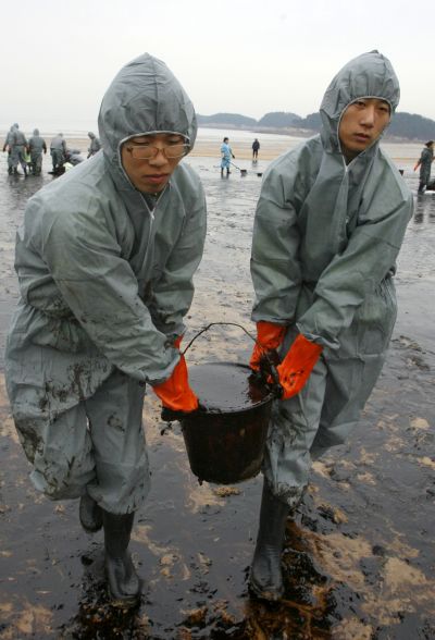Soldiers from the South Korean army carry a bucket filled with oil.