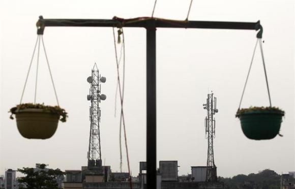 Telecommunication towers are pictured through hanging flower pots at a residential building in Kolkata
