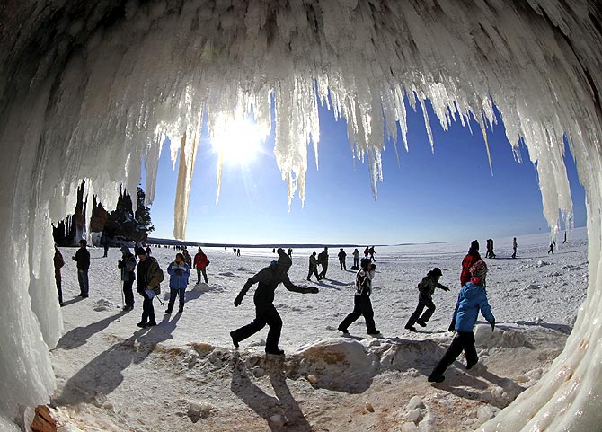 Sightseers look at icicles at the mouth of a sea cave in US.