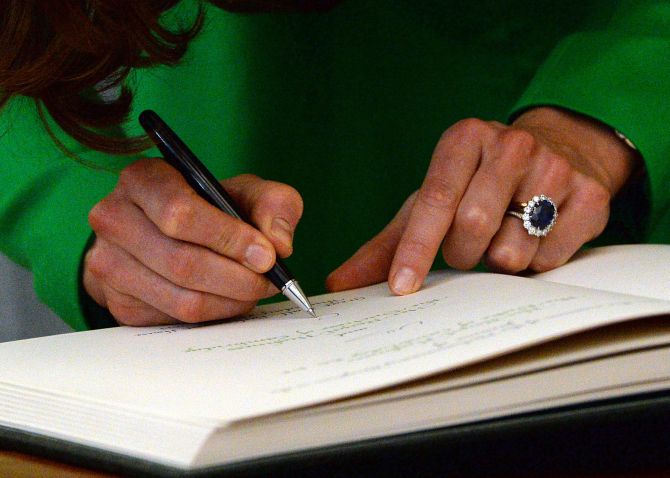 Catherine, Duchess of Cambridge, signs a visitors' book.