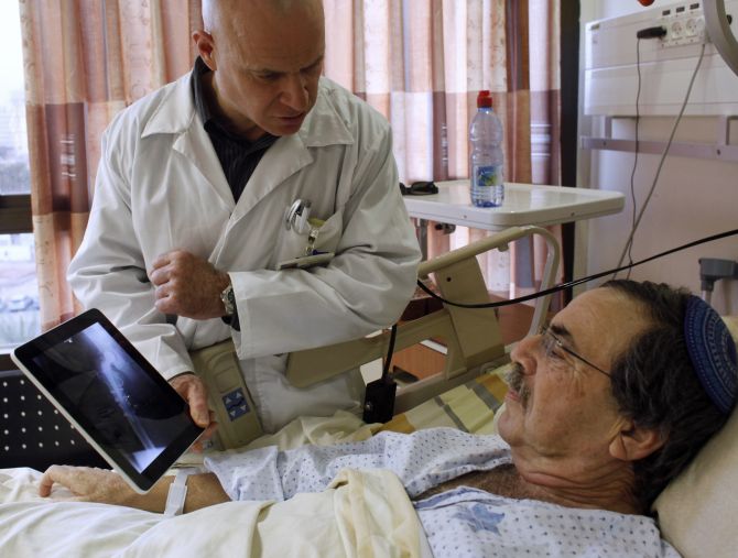 Doctor Nir Cohen shows a patient an x-ray image on an Apple iPad.