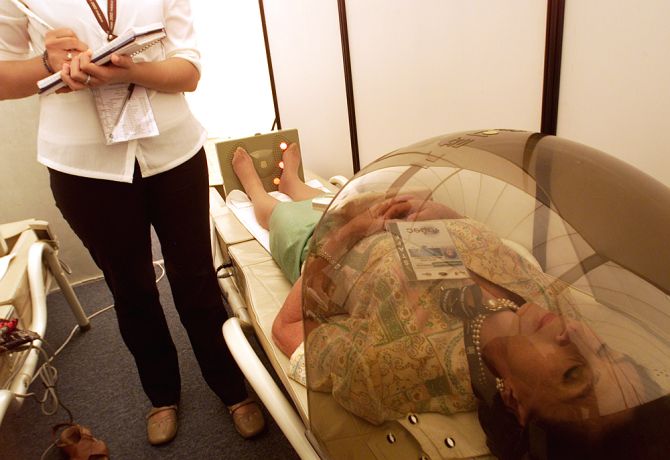 A therapist checks on her patient as she undergoes stress relieving procedure.