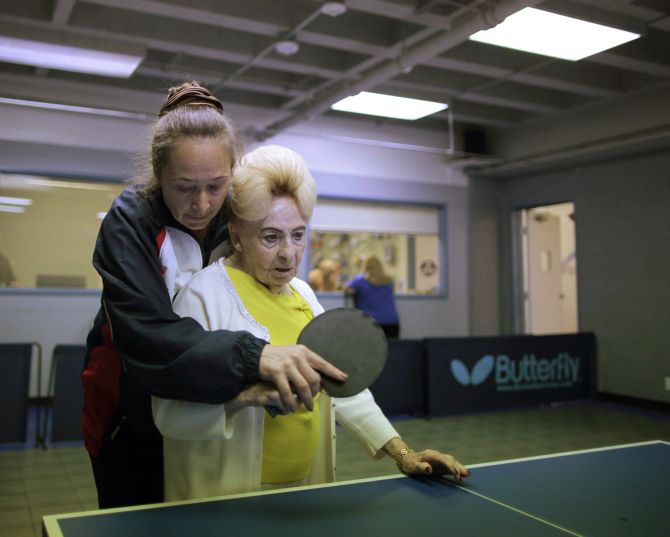 Holocaust survivor Betty Stein, 92, (R) is helped by coach Irina Jestkova as she plays ping pong at a program for people with Alzheimer's and dementia at the Arthur Gilbert table tennis center in Los Angeles, California.