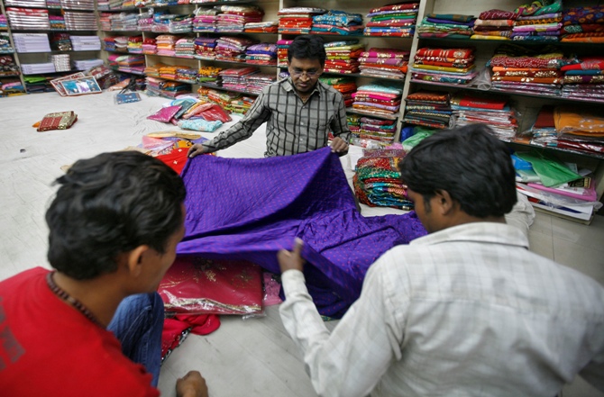 A shopkeeper displays a saree.